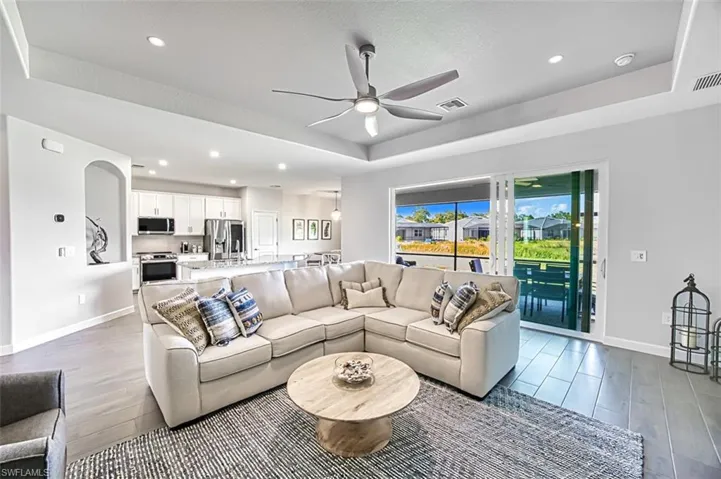 Living room featuring sink, ceiling fan, light hardwood / wood-style floors, and a raised ceiling