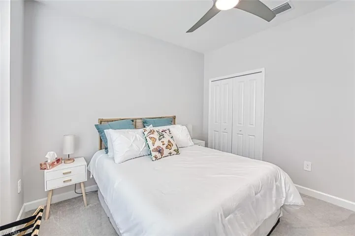 Bedroom with a closet, ceiling fan, and light colored carpet