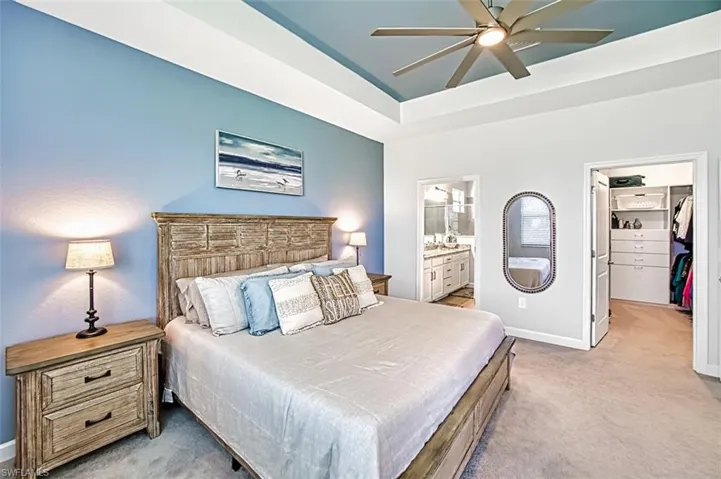 Carpeted bedroom with a closet, a walk in closet, ensuite bath, and ceiling fan