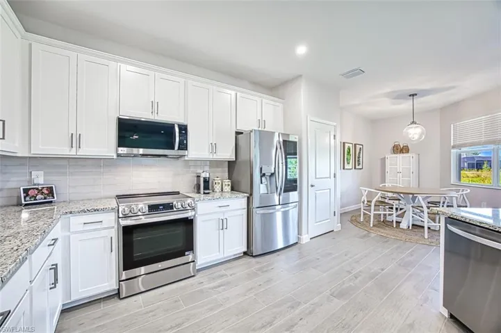 Kitchen featuring appliances with stainless steel finishes, decorative backsplash, white cabinetry, and light wood-type flooring