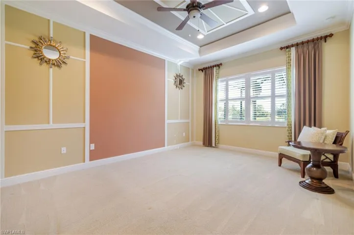 Spacious primary bedroom with trim work and tray ceiling