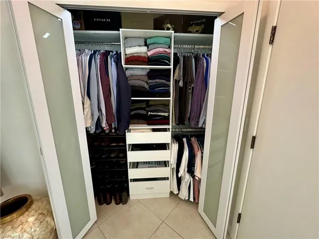 Customizable closet system featuring white framed doors with frosted glass panels, integrated shelving, and multiple hanging rods