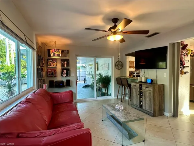 Neutral-toned tile flooring extends through this open living area, featuring a ceiling fan with integrated lighting
