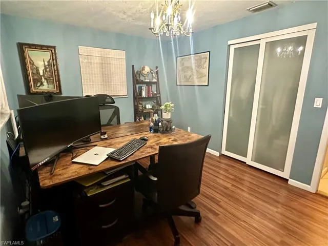 Room featuring wood-finish flooring, a contemporary chandelier, and a built-in closet with frosted glass sliding doors