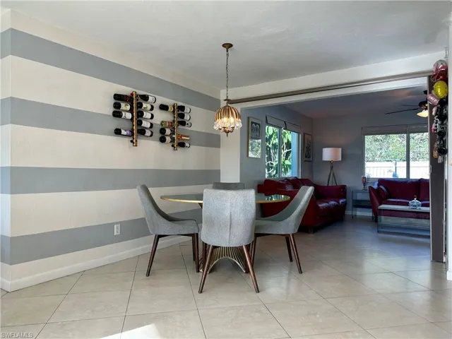 Dining area with square tile flooring, a decorative ceiling light fixture, and a wall featuring horizontal stripe detailing