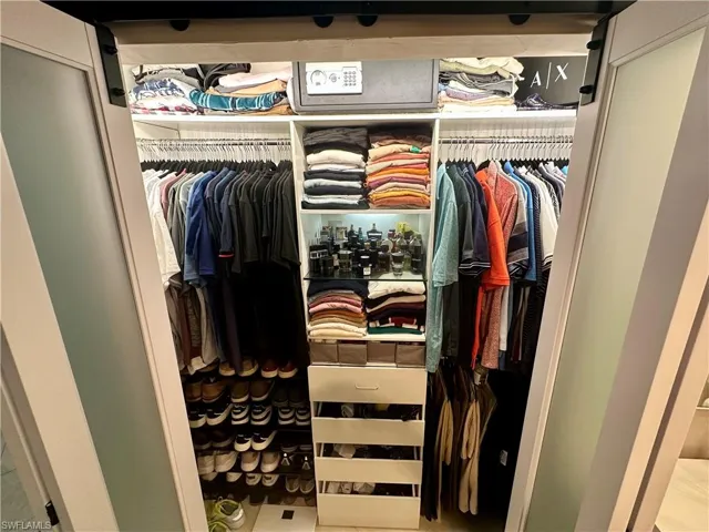 Custom closet system featuring frosted glass barn doors, integrated lighting, built-in shelving, hanging rods, and a multi-drawer storage unit