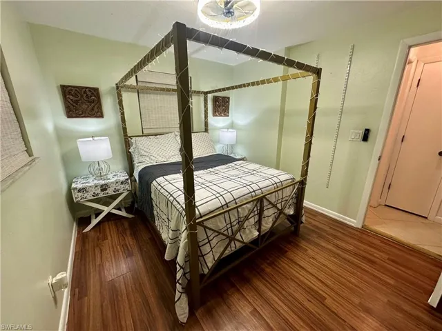 Bedroom featuring wood-finish flooring, light green walls, a ceiling-mounted light fixture, and a white interior door