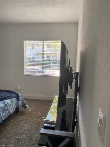 Bedroom featuring dark colored carpet and a textured ceiling