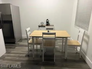 Dining room featuring dark wood-style floors and baseboards