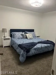 Bedroom with dark carpet and a textured ceiling