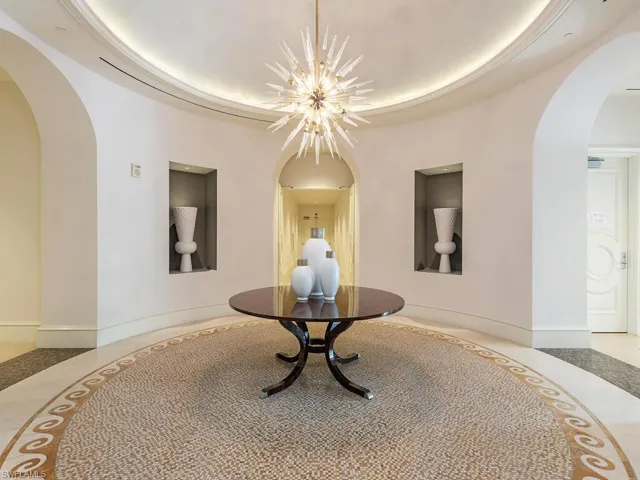 Hallway with arched walkways, inlaid floor details, and a raised ceiling