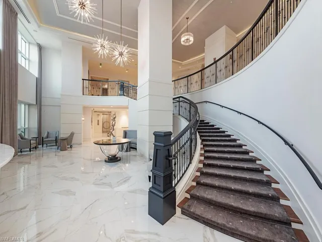 Stairs featuring a high ceiling, marble tiled flooring, and a chandelier