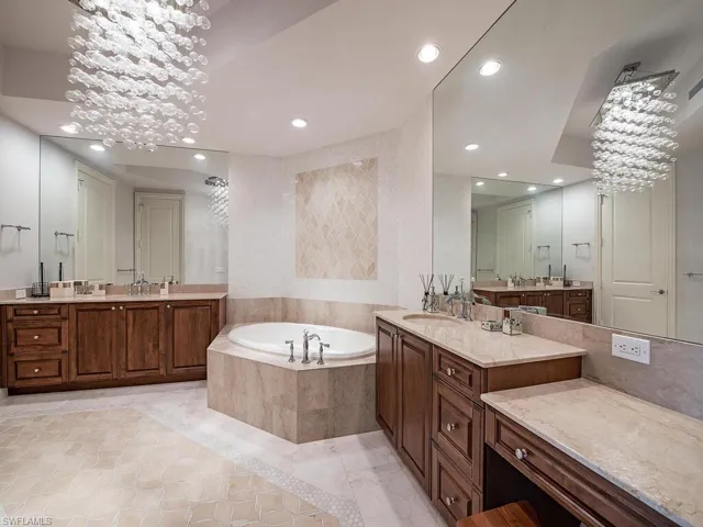 Bathroom featuring a chandelier, a garden tub, two vanities, recessed lighting, and light tile patterned flooring
