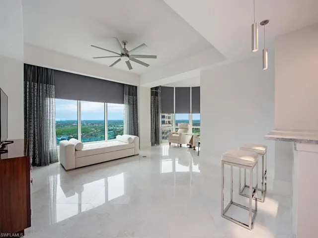 Living room featuring a ceiling fan and light marble finish floors