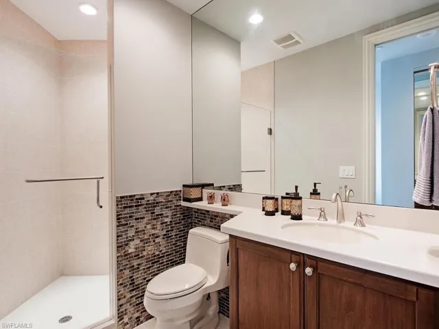 Bathroom featuring tile walls, vanity, a stall shower, and recessed lighting