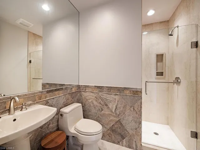 Full bath featuring tile walls and a shower stall