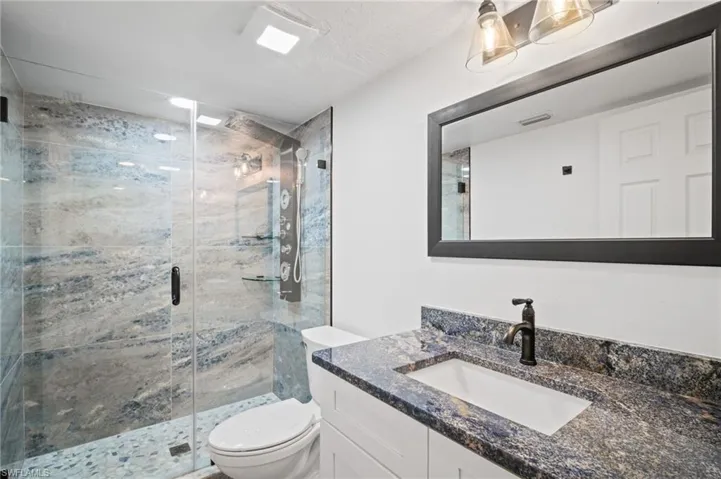 Bathroom featuring vanity and a marble finish shower