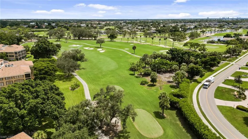 Aerial perspective of suburban area featuring a golf course and a nearby body of water