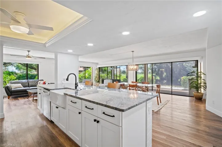 Kitchen featuring light stone countertops, white cabinets, recessed lighting, a center island with sink, and open floor plan