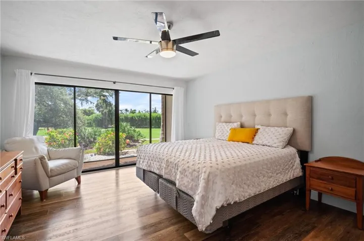 Bedroom featuring access to exterior, dark wood-style floors, and a ceiling fan
