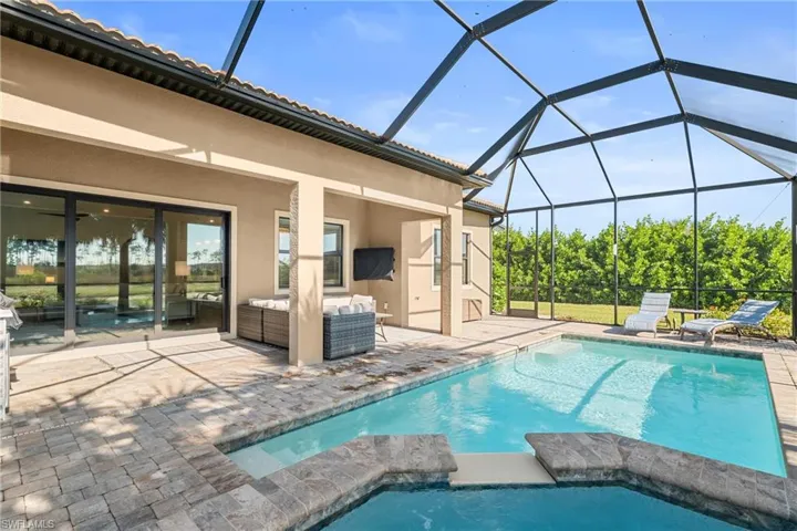 View of pool with a lanai, a sunroom, a patio, a pool with connected hot tub, and outdoor lounge area