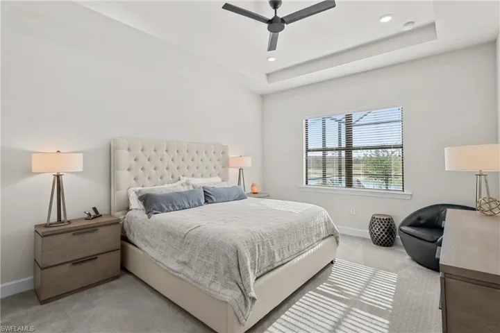 Bedroom with light carpet, a ceiling fan, a tray ceiling, and recessed lighting