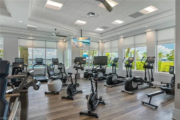 Exercise room featuring a drop ceiling, a ceiling fan, and a towering ceiling