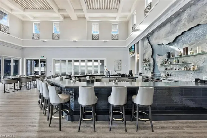 Bar with dark cabinets, coffered ceiling, beamed ceiling, open shelves, and a high ceiling