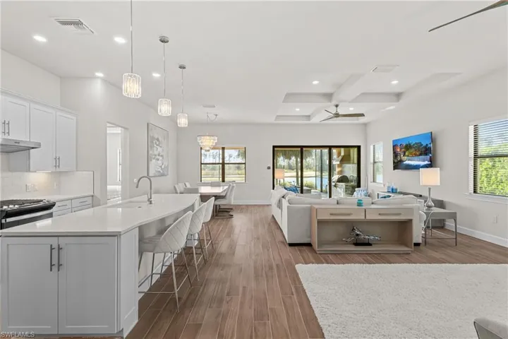 Kitchen featuring white cabinetry, recessed lighting, decorative light fixtures, a kitchen breakfast bar, and light stone countertops