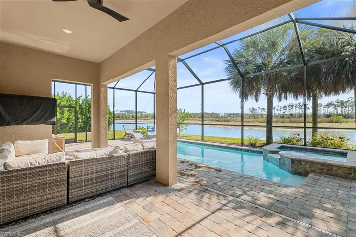 View of swimming pool featuring a sunroom, a pool with connected hot tub, a patio, a water view, and glass enclosure