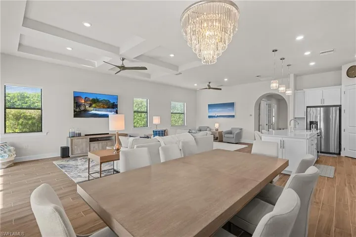 Dining room with coffered ceiling, a ceiling fan, wood tiled floors, arched walkways, and recessed lighting