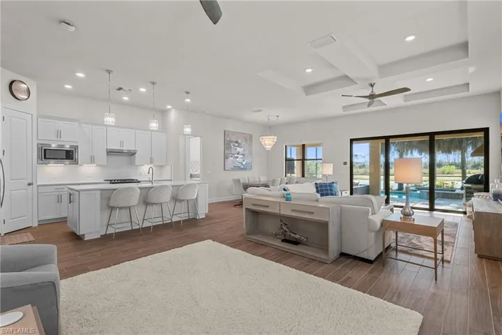 Living room with a ceiling fan, coffered ceiling, recessed lighting, wood tiled floors, and beam ceiling