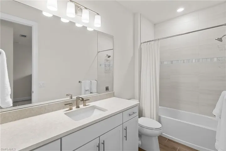 Full bath with vanity, shower / tub combo with curtain, and wood tiled floors