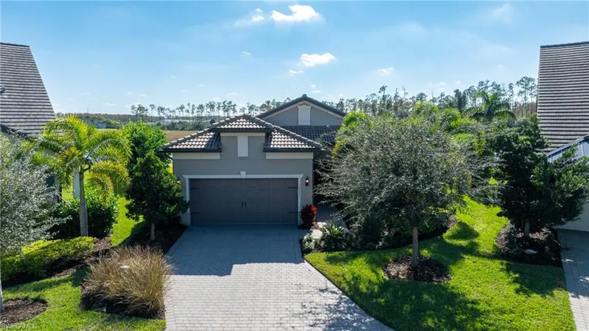 View of front of property with stucco siding, decorative driveway, a garage, a front lawn, and a tile roof