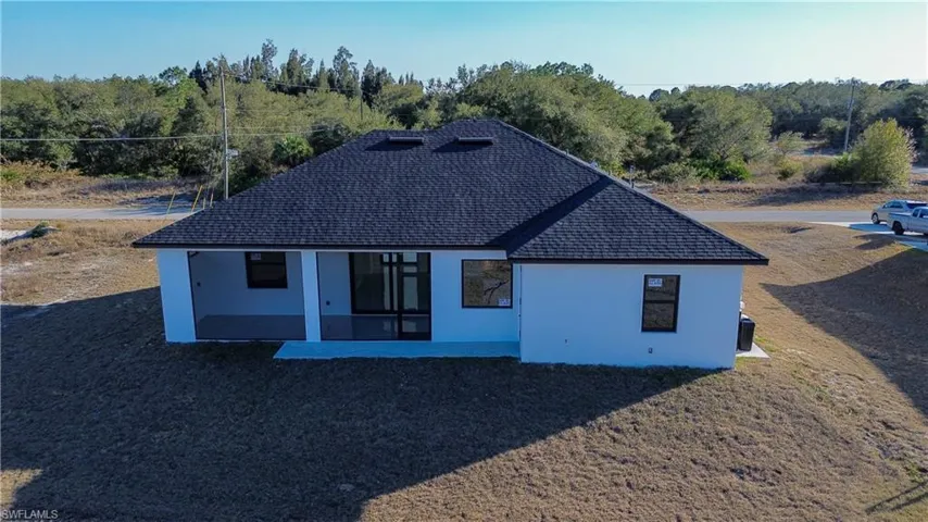Back of house featuring stucco siding, roof with shingles, and a patio