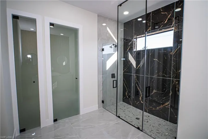 Full bath featuring a marble finish shower, recessed lighting, and marble tiled floors