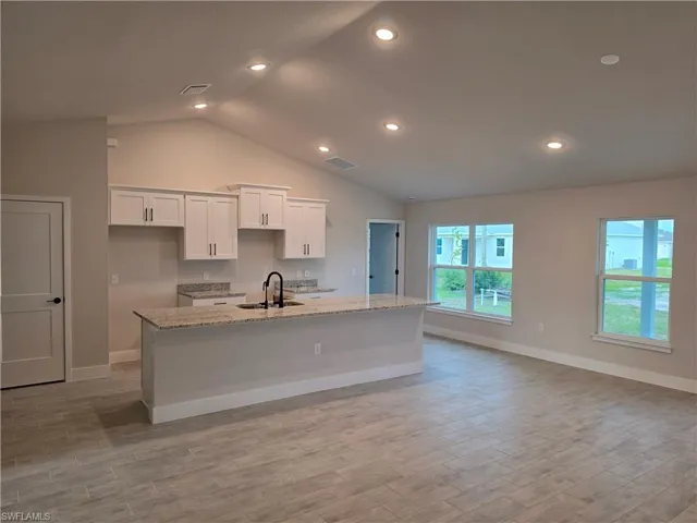 Open-concept living space with vaulted ceilings and recessed lighting