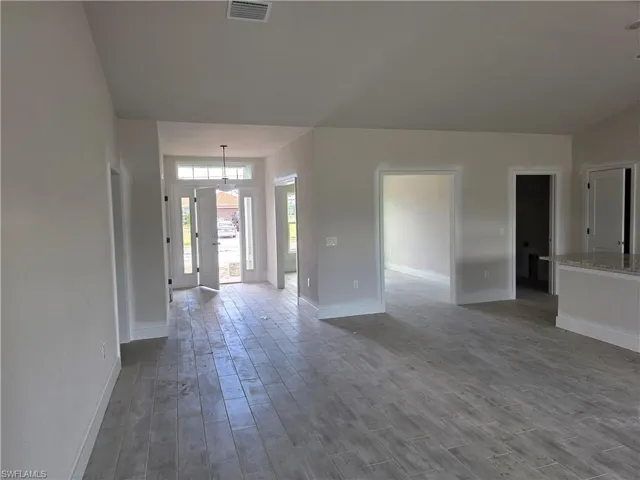 The property features light-colored plank-style flooring throughout the open concept living areas, complemented by a front door with side windows and a transom window