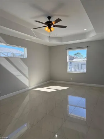 Primary room featuring a raised ceiling, recessed lighting, and a ceiling fan