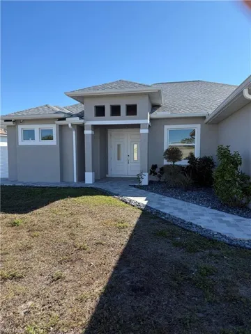View of front facade featuring stucco siding and a front yard