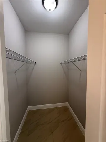 Walk in closet with light marble finish flooring