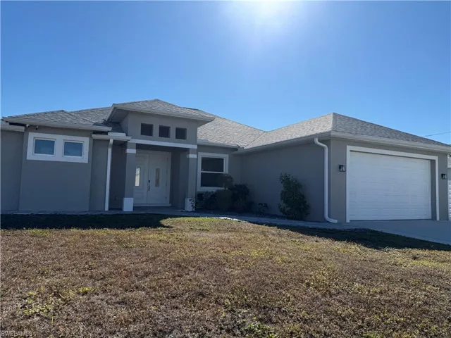 home with an attached garage, a front yard, stucco siding, and concrete driveway