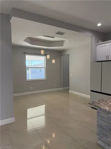 Empty room with baseboards and a tray ceiling