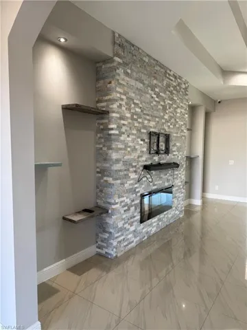 Unfurnished living room featuring a glass covered fireplace and light marble finish floors