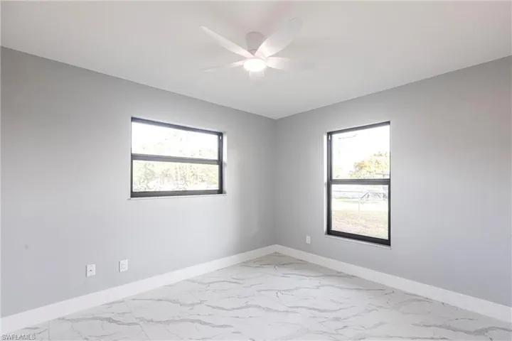 Unfurnished room featuring plenty of natural light, marble finish floor, and ceiling fan