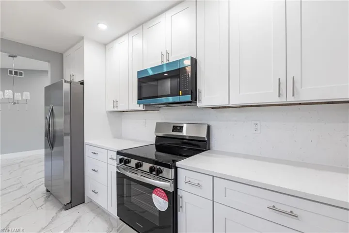 Kitchen featuring stainless steel appliances, visible vents, recessed lighting, white cabinetry, and marble finish floor