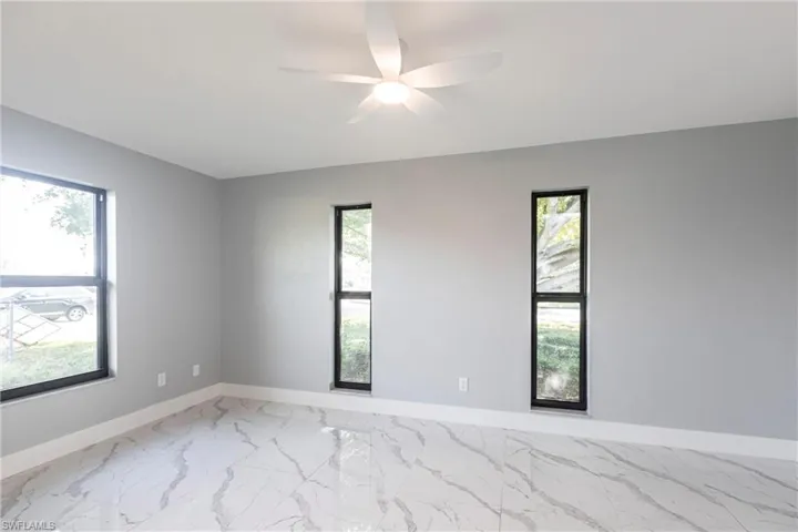 Empty room with marble finish floor, baseboards, and ceiling fan