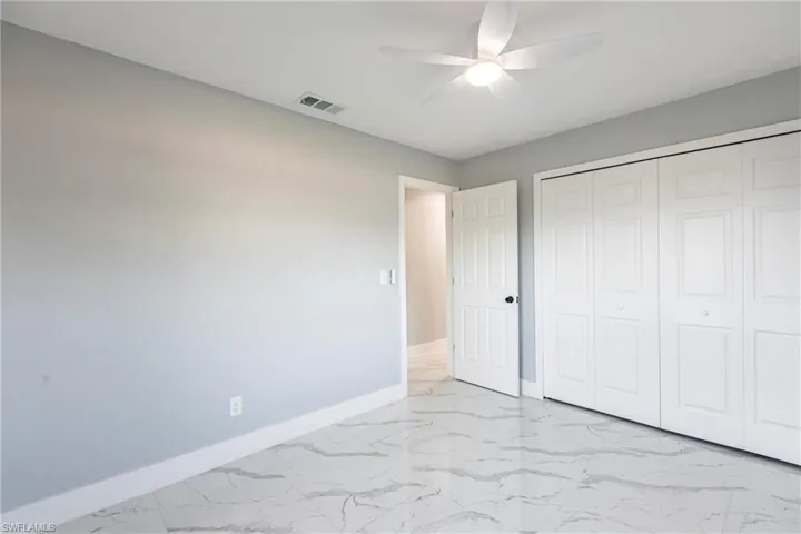 Unfurnished bedroom with a ceiling fan, a closet, marble finish floor, baseboards, and visible vents