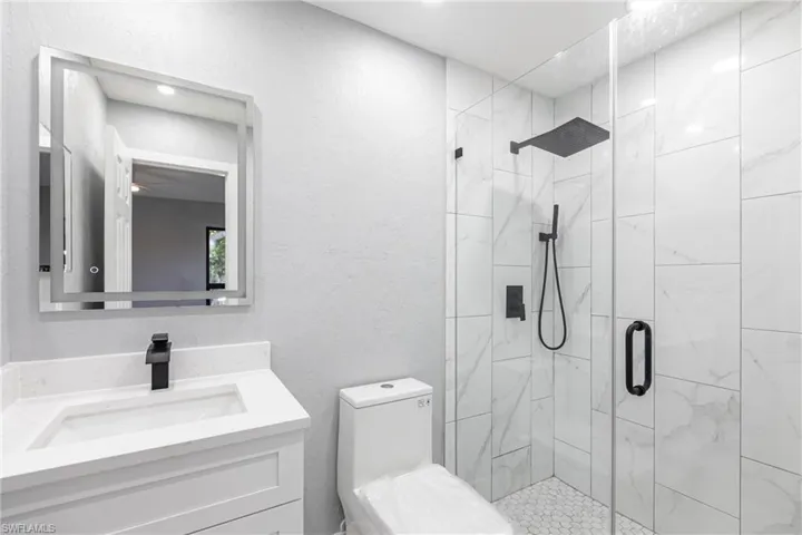 Bathroom with vanity, toilet, and a stall shower