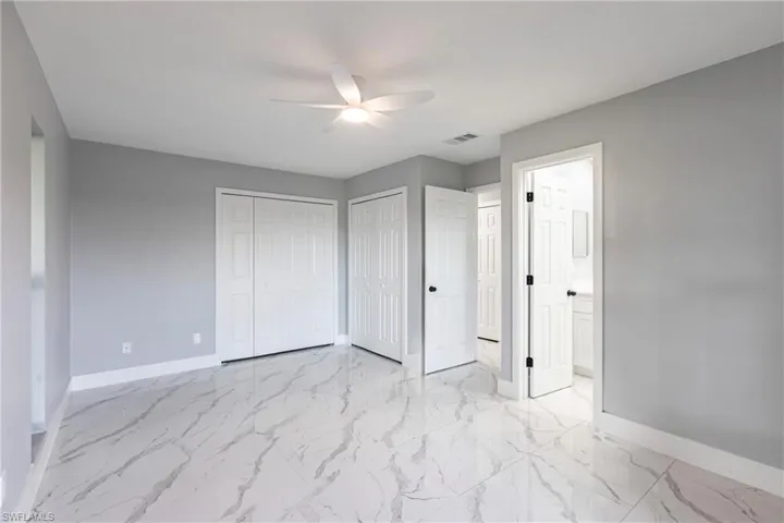 Unfurnished bedroom featuring multiple closets, marble finish floor, baseboards, and visible vents